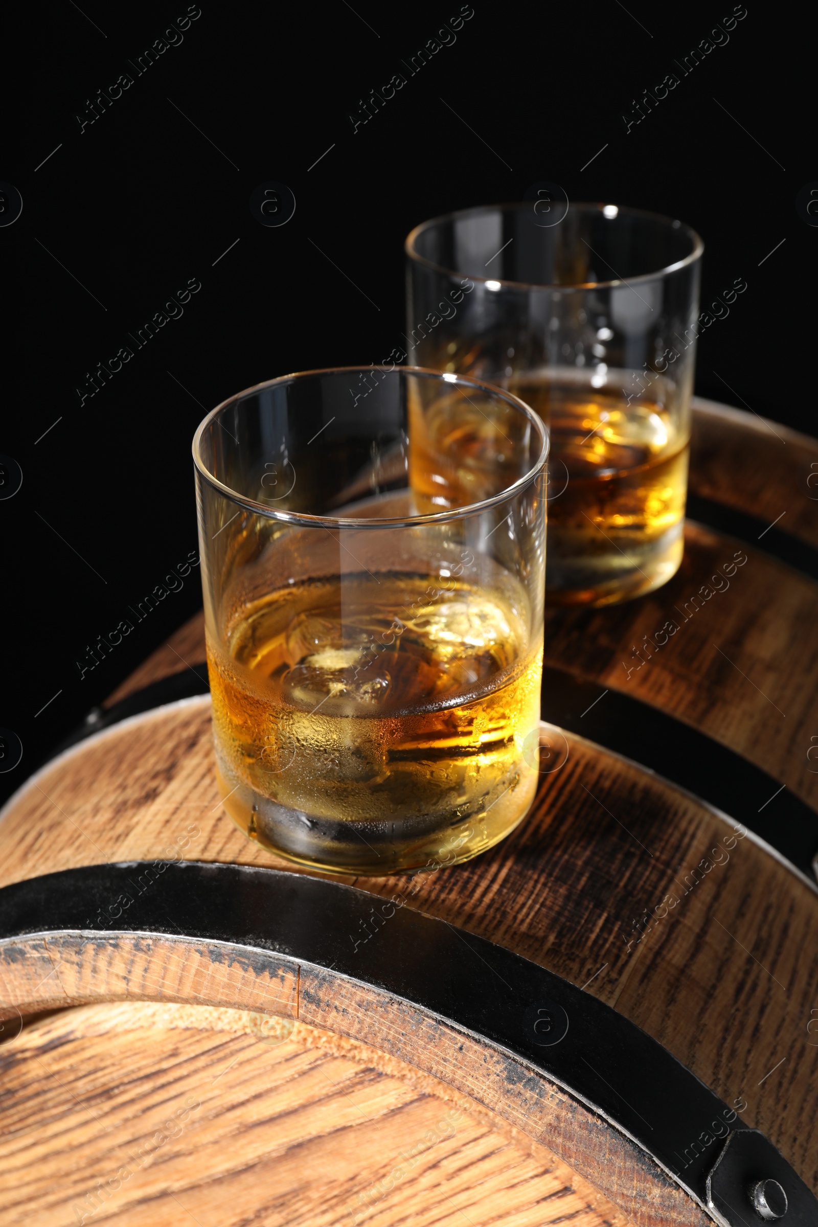 Photo of Glasses of tasty whiskey on wooden barrel