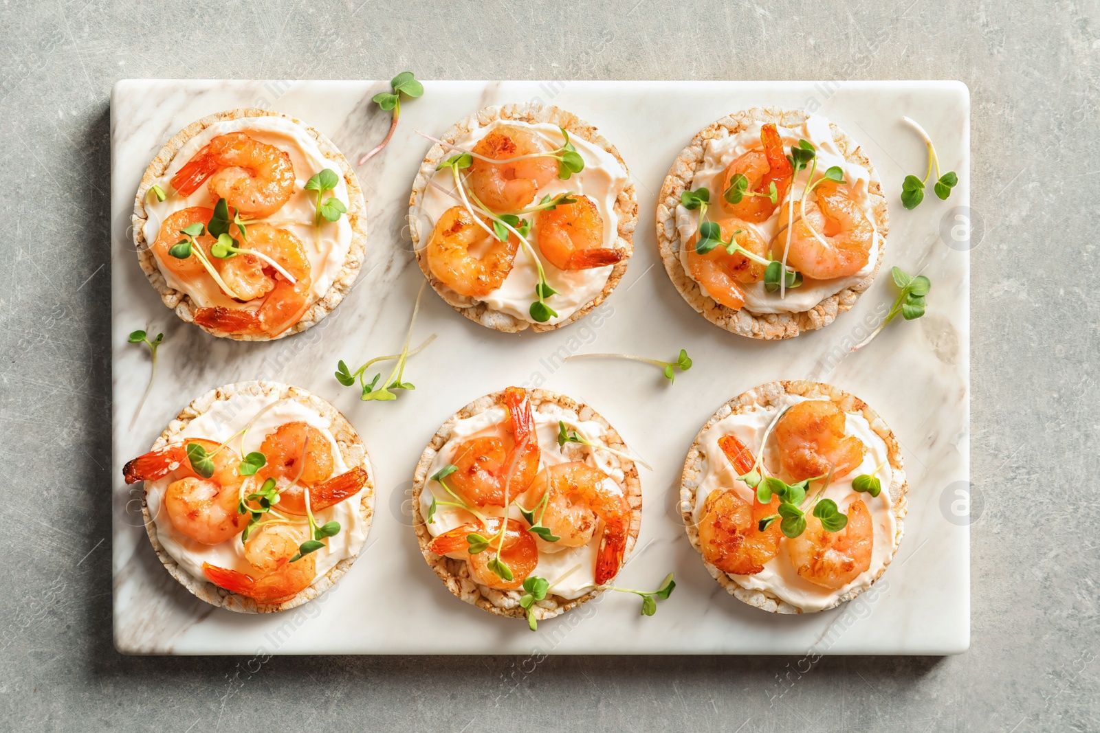 Photo of Delicious small sandwiches with shrimps on marble board