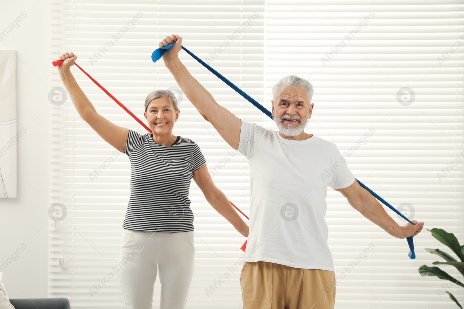 Photo of Senior couple doing exercise with fitness elastic bands at home