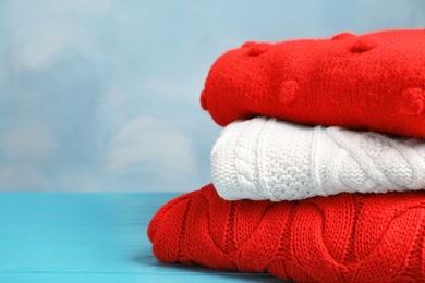 Photo of Stack of folded knitted sweaters on table. Space for text