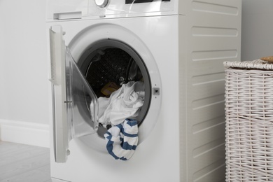 Photo of Washing machine with laundry near wall in room