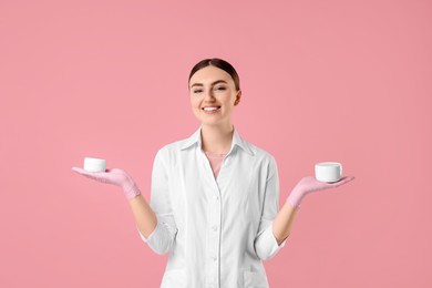 Cosmetologist with cosmetic products on pink background