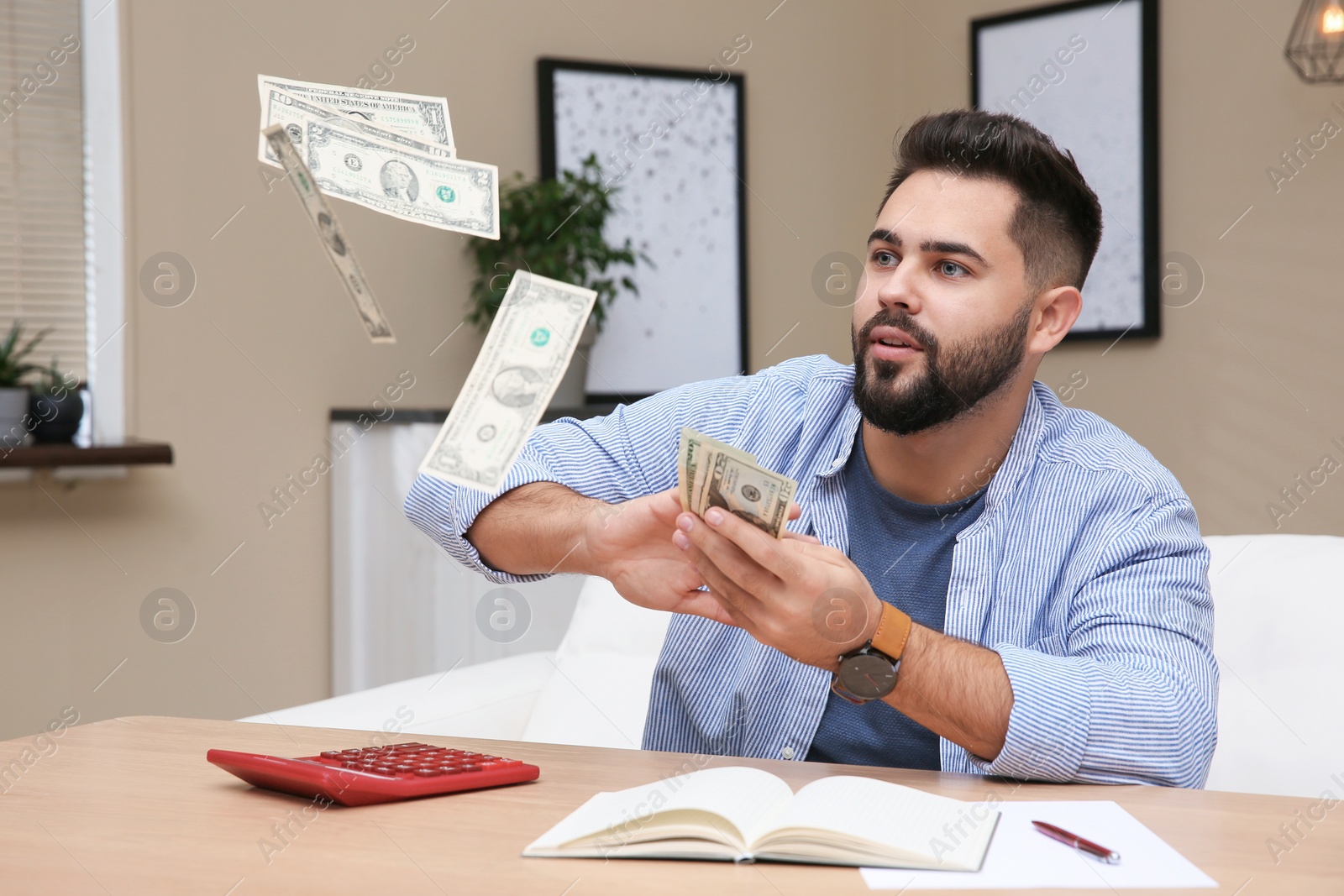 Photo of Young man throwing money at table indoors