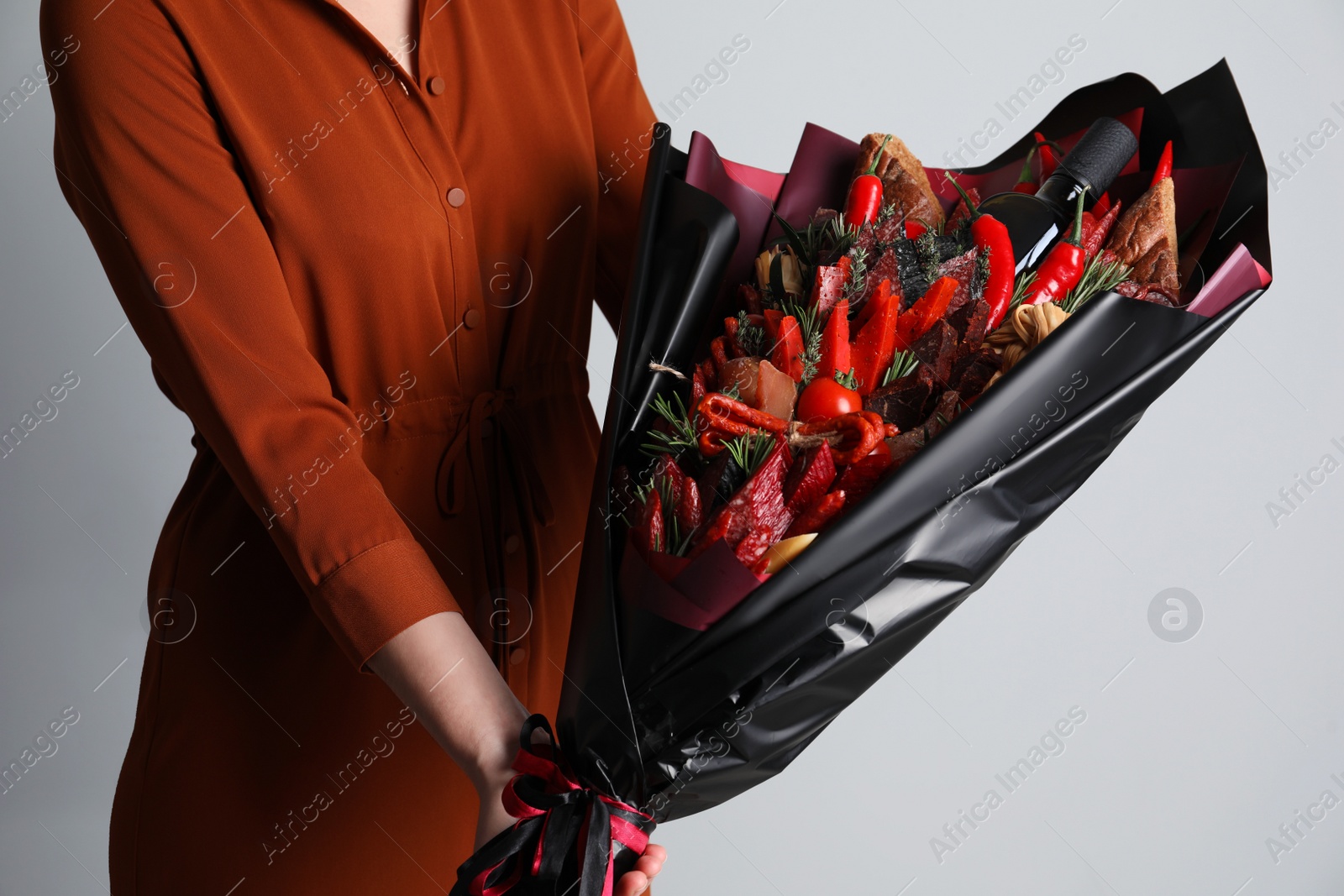 Photo of Woman with beautiful food bouquet on light grey background, closeup