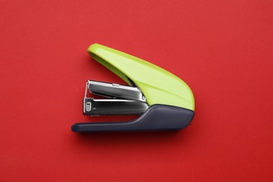 Photo of New bright stapler on red background, top view. School stationery