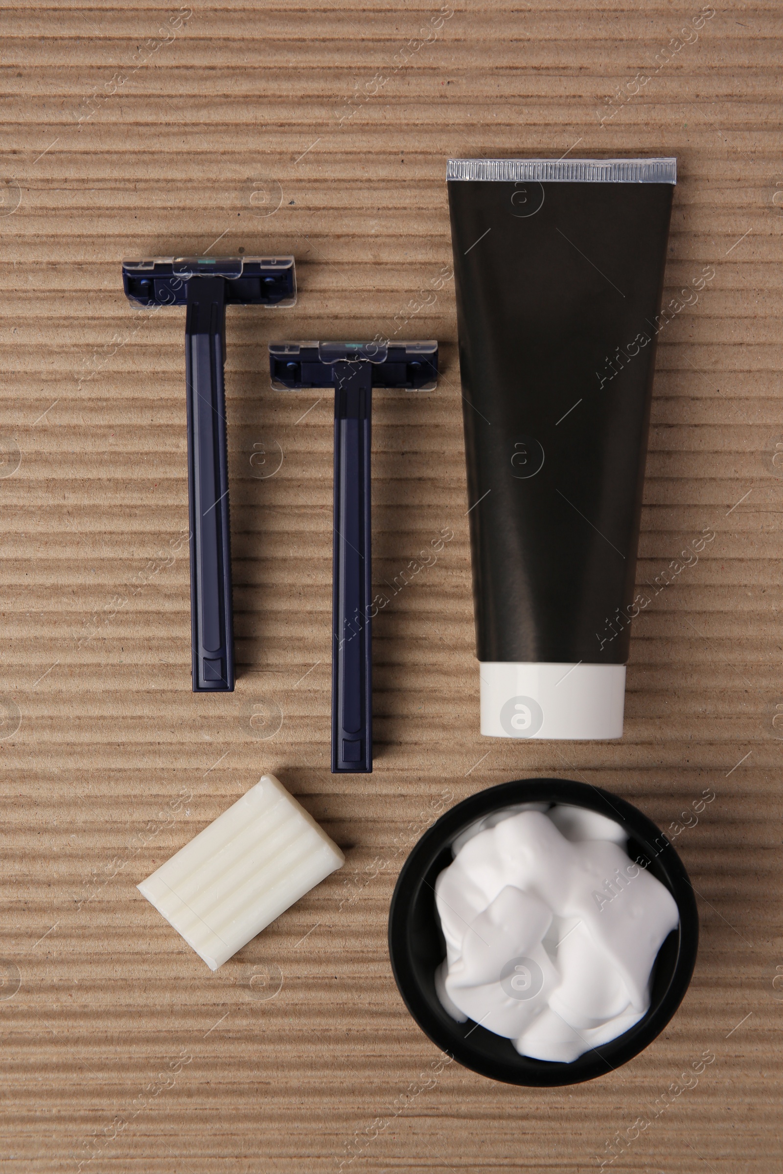 Photo of Razors, shaving foam, soap and cream on cardboard, flat lay