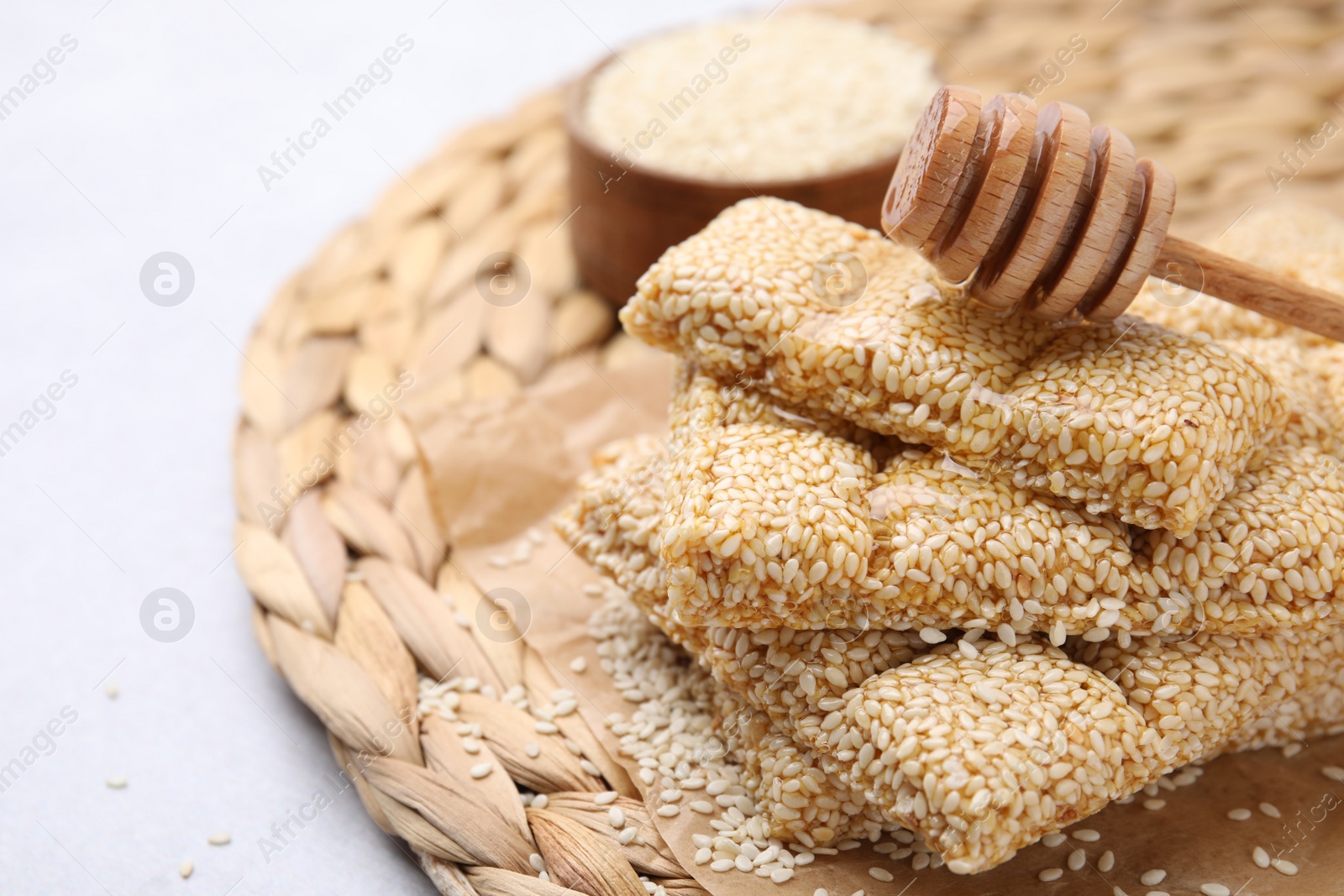 Photo of Delicious sesame kozinaki bars and wooden dipper on white table, closeup