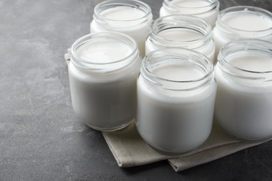 Photo of Tasty yogurt in glass jars on grey table