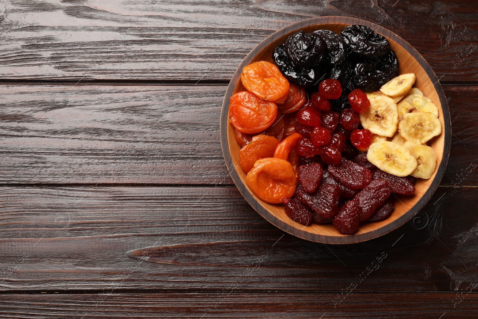 Photo of Mix of delicious dried fruits on wooden table, top view. Space for text