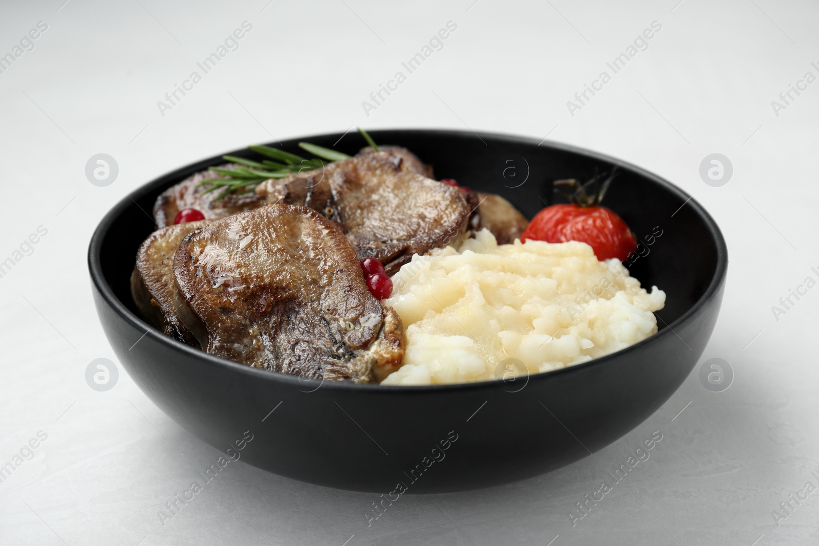 Photo of Tasty beef tongue pieces, berries, rosemary, mashed potatoes and tomato on white table, closeup