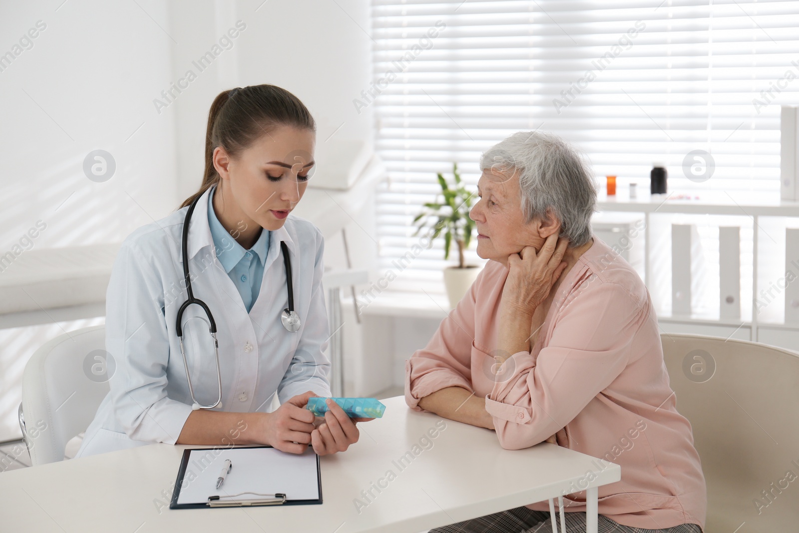 Photo of Doctor giving pills to senior patient in office