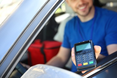 Male courier with terminal in car, closeup. Food delivery service