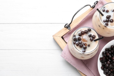Photo of Bubble milk tea with tapioca balls on white wooden table, top view. Space for text