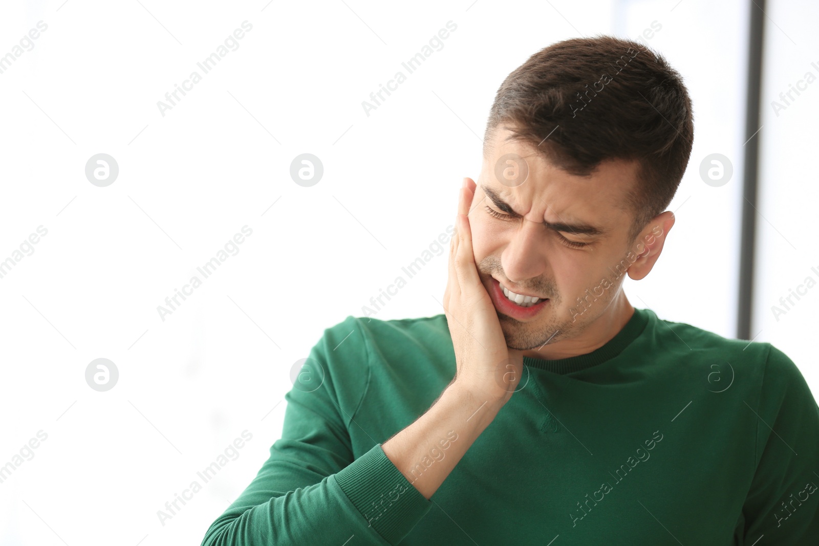 Photo of Young man suffering from toothache  at home