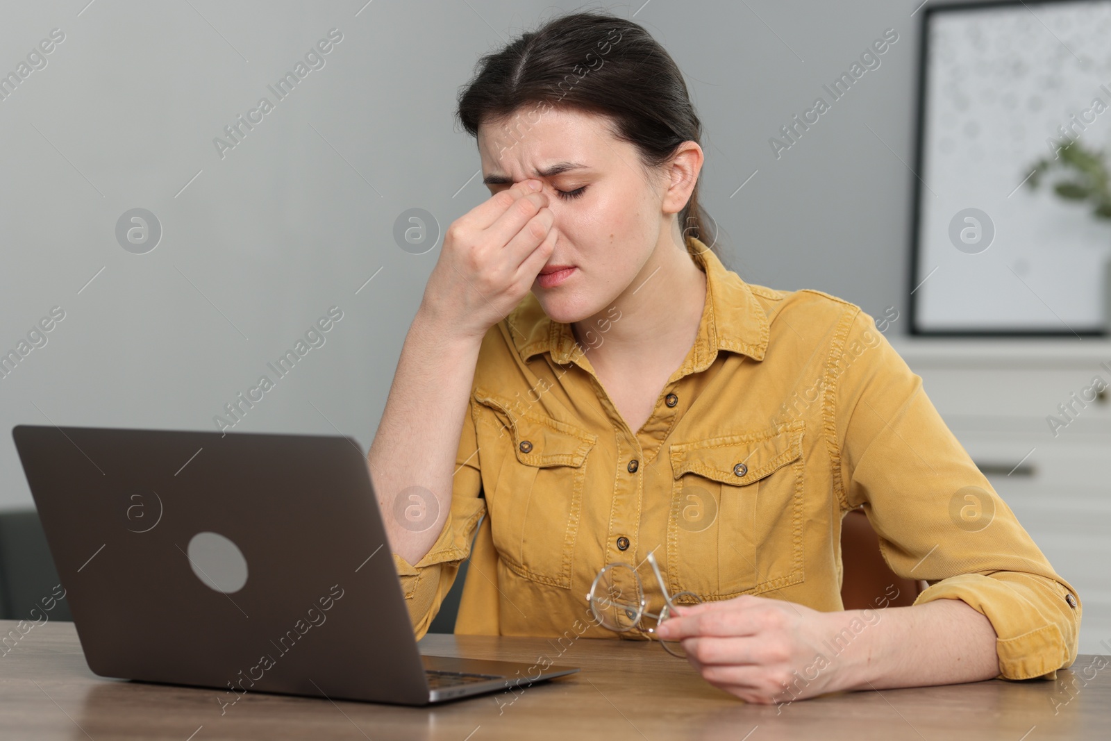 Photo of Overwhelmed woman sitting with laptop at table indoors