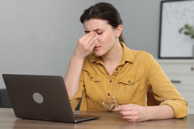 Photo of Overwhelmed woman sitting with laptop at table indoors