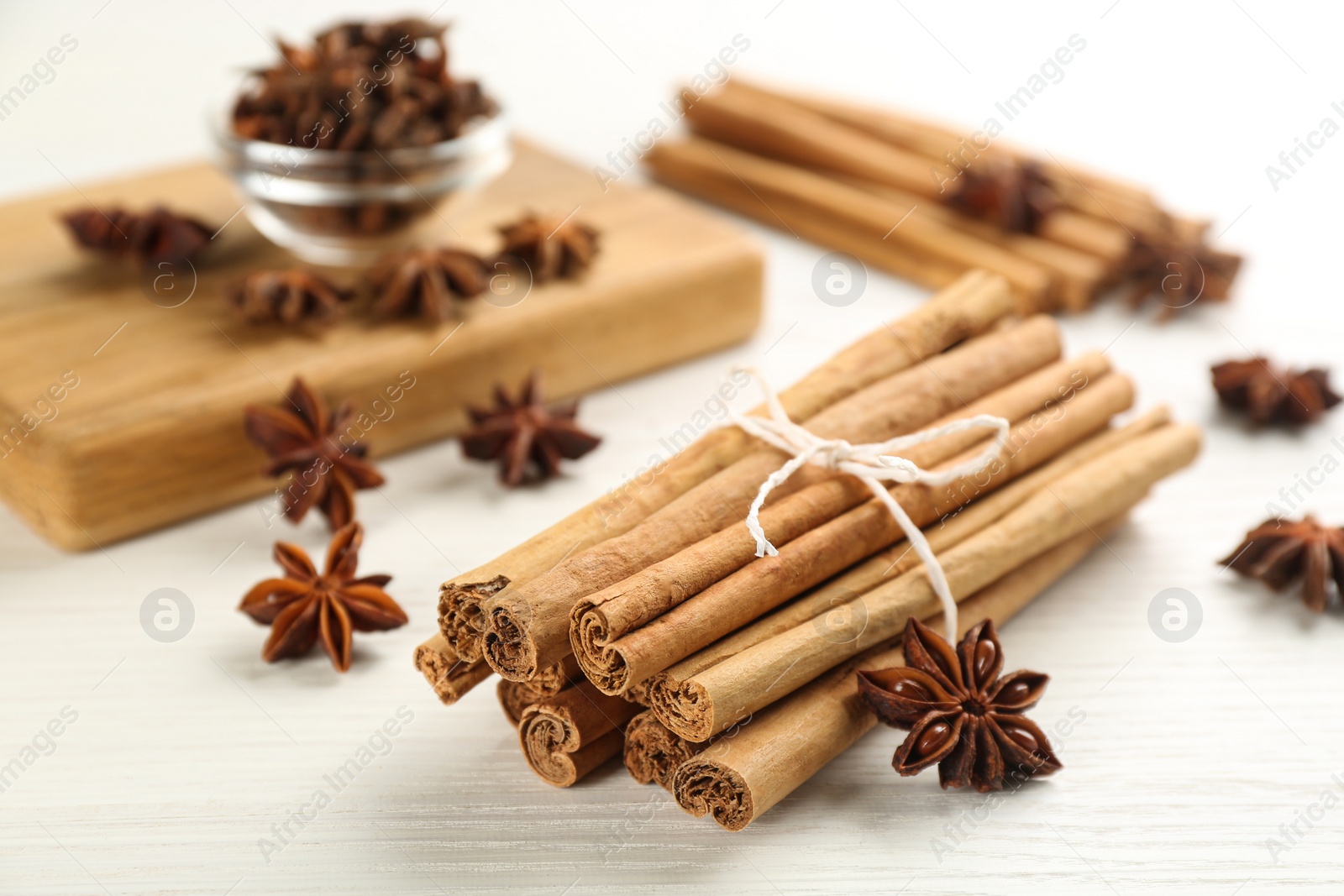 Photo of Aromatic cinnamon sticks and anise on white wooden table