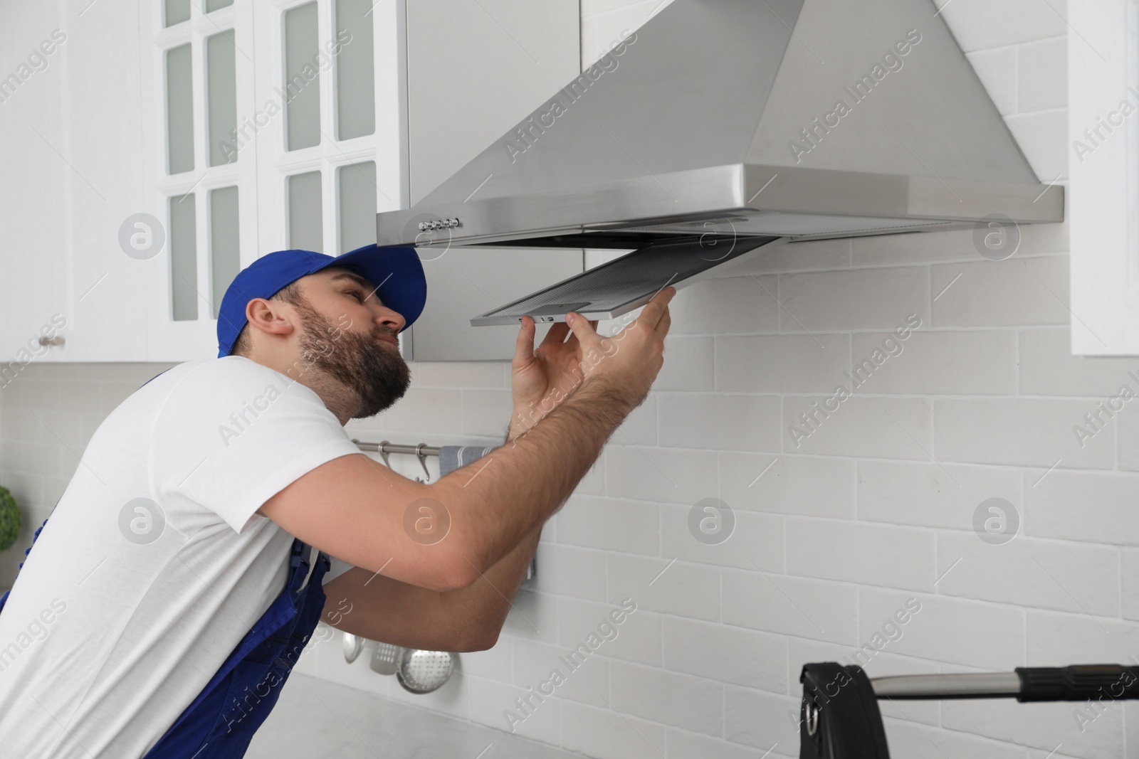 Photo of Worker repairing modern cooker hood in kitchen