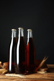 Photo of Bottles of delicious fresh kvass, spikelets and bread on wooden table