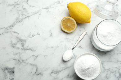 Photo of Baking soda and cut lemons on white marble table, flat lay. Space for text