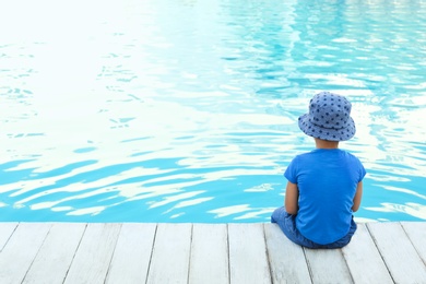 Photo of Little child near outdoor swimming pool. Dangerous situation