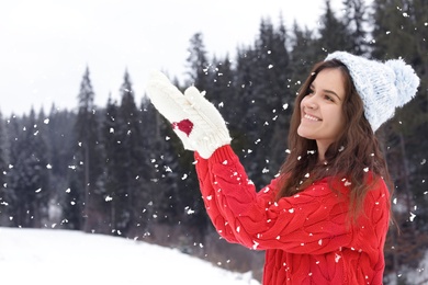 Happy young woman in warm clothes outdoors. Winter vacation