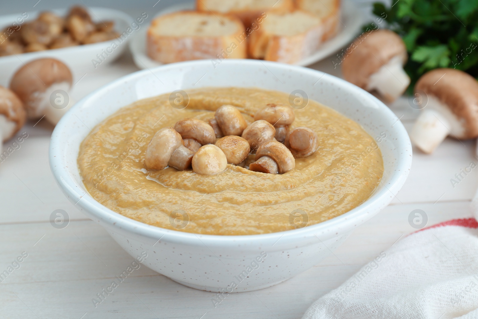 Photo of Delicious mushroom cream soup on white wooden table