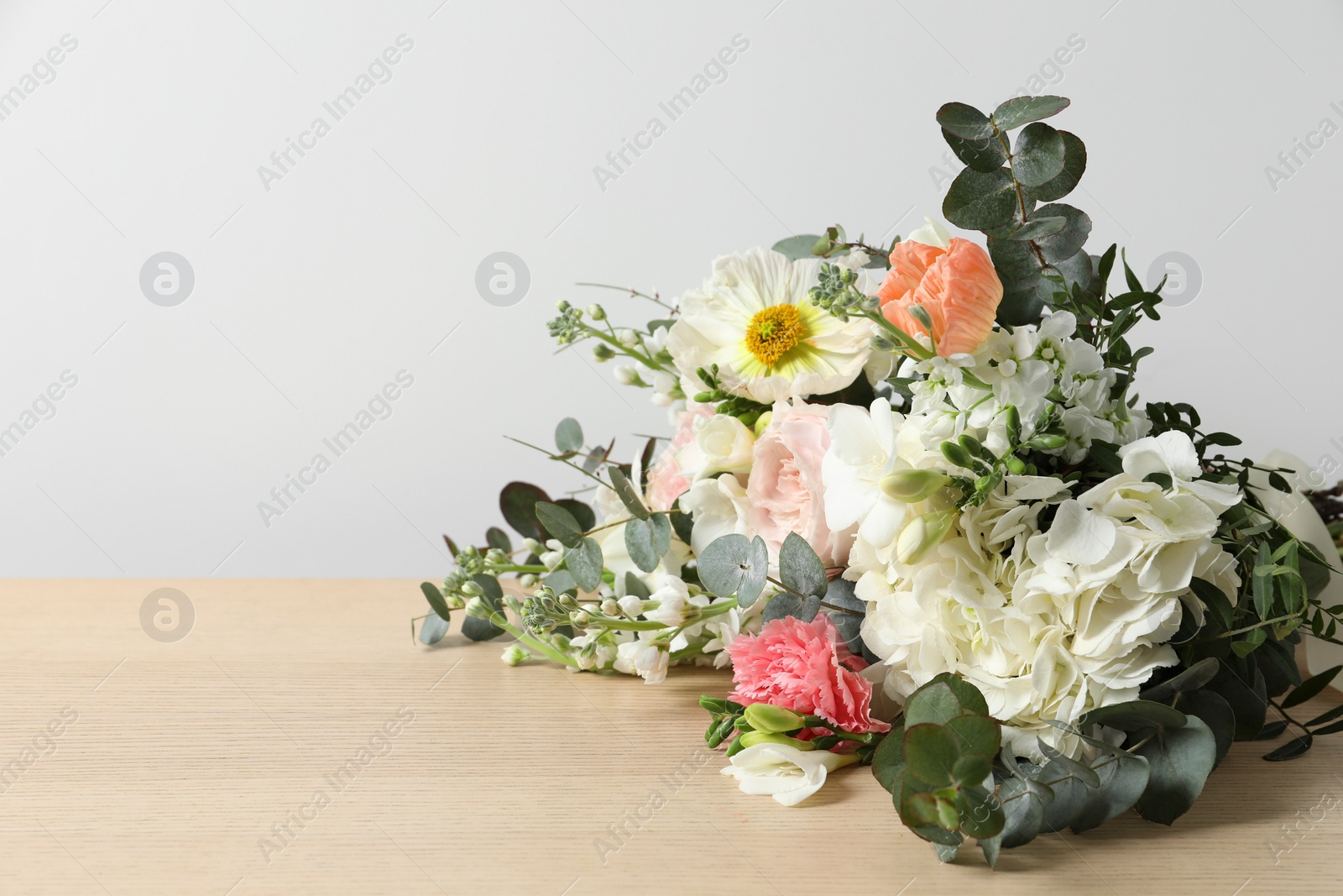 Photo of Bouquet of beautiful flowers on wooden table against white wall. Space for text