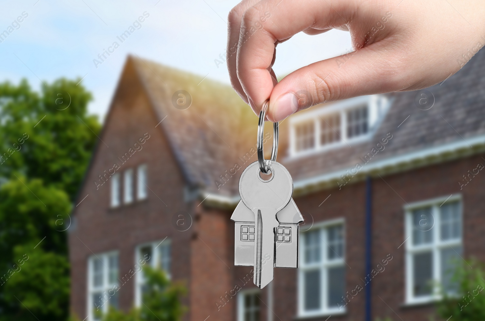 Image of Woman holding key near house outdoors, closeup