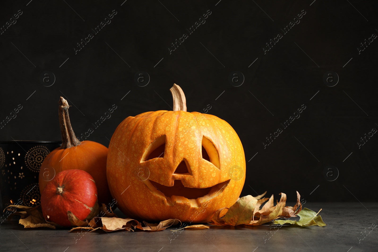 Photo of Composition with pumpkin head on dark background. Jack lantern - traditional Halloween decor