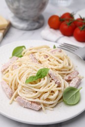 Photo of Plate of tasty pasta Carbonara with basil leaves on white table, closeup