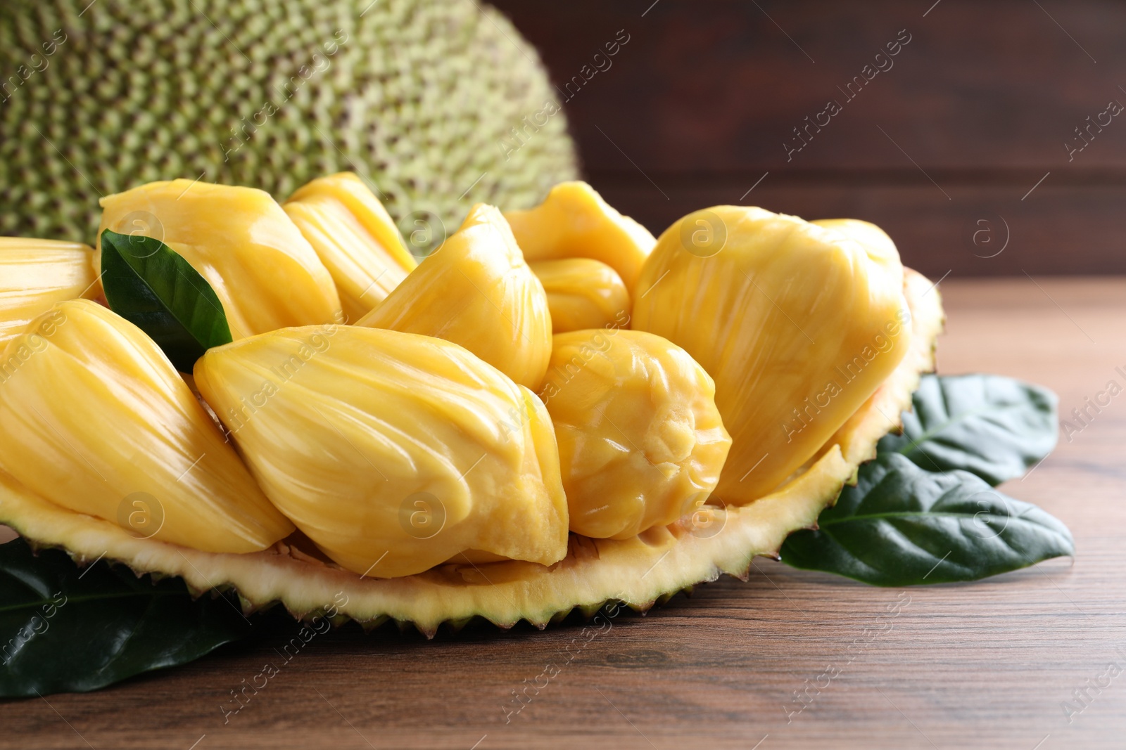 Photo of Fresh exotic jackfruit bulbs on wooden table, closeup