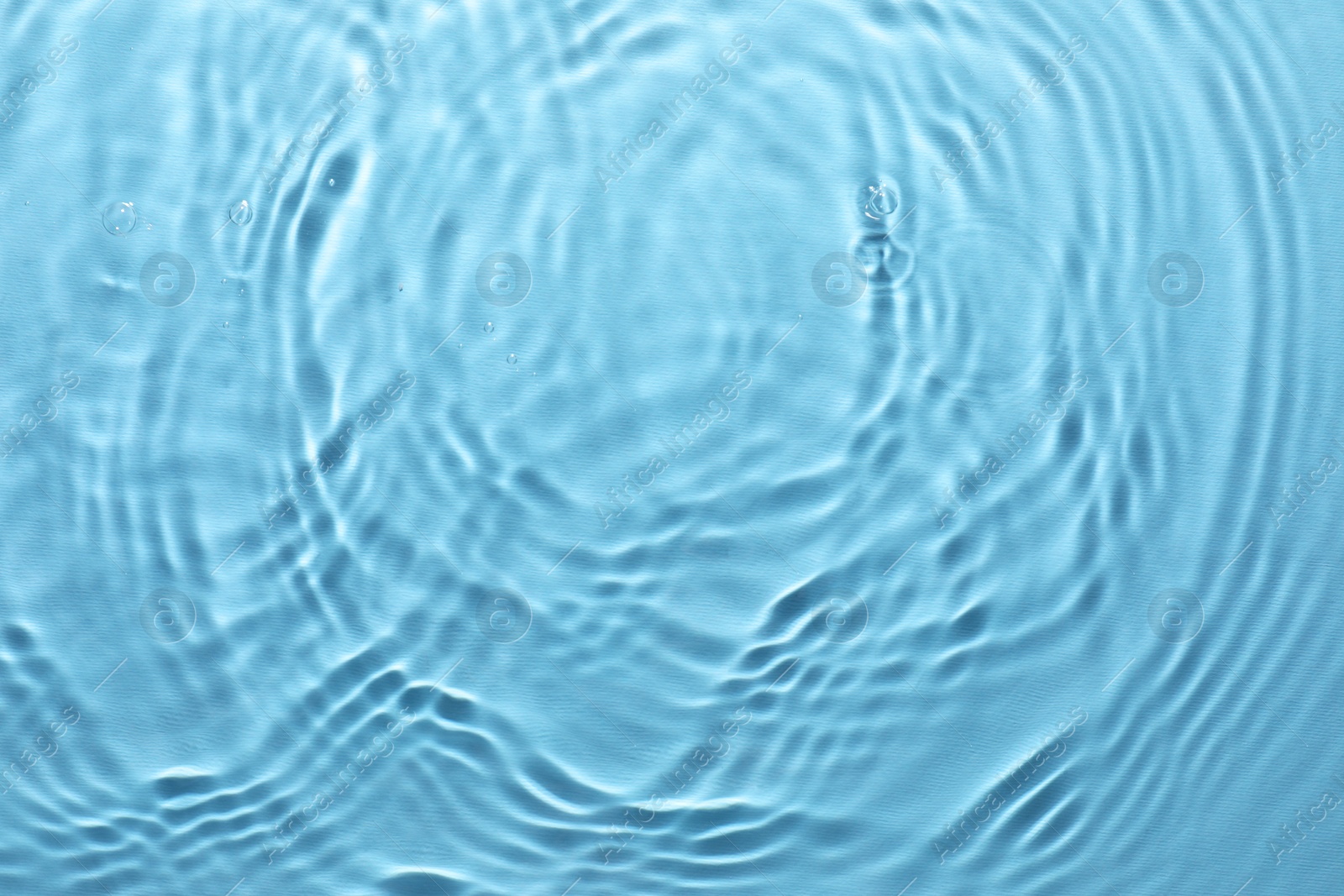 Photo of Rippled surface of clear water on light blue background, top view