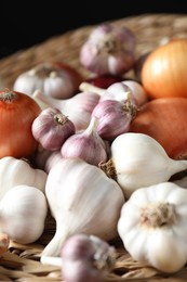 Photo of Fresh raw garlic and onions on wicker mat, closeup