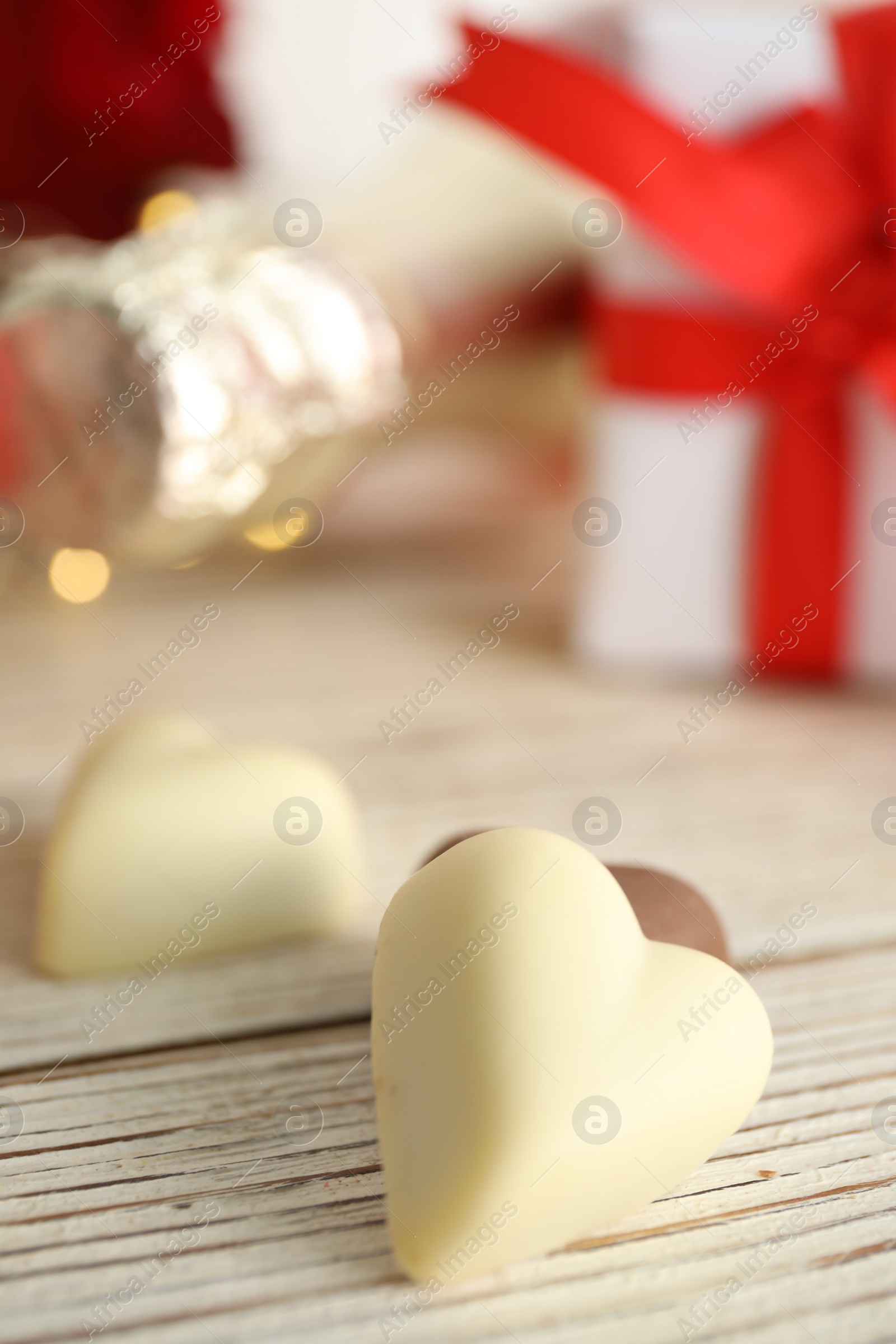 Photo of Tasty heart shaped chocolate candies on white wooden table, closeup. Valentine's day celebration