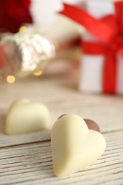 Tasty heart shaped chocolate candies on white wooden table, closeup. Valentine's day celebration