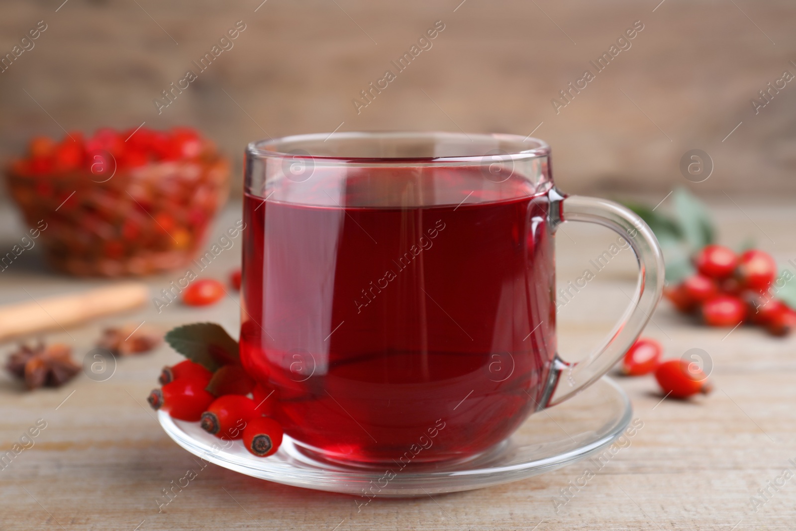 Photo of Aromatic rose hip tea and fresh berries on wooden table, closeup