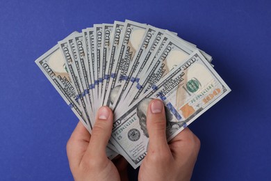 Photo of Money exchange. Man holding dollar banknotes on blue background, top view