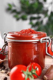 Photo of Jar of tasty tomato paste and ingredients on table, space for text