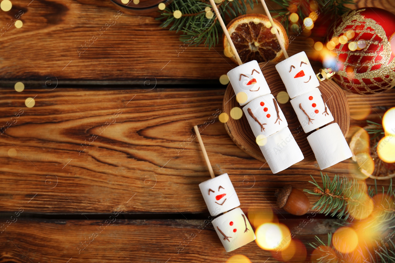 Image of Flat lay composition with funny snowmen made of marshmallows on wooden table, space for text. Bokeh effect 