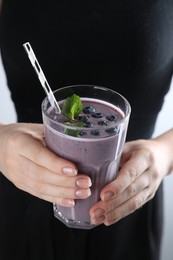 Photo of Woman with glass of tasty blueberry smoothie, closeup