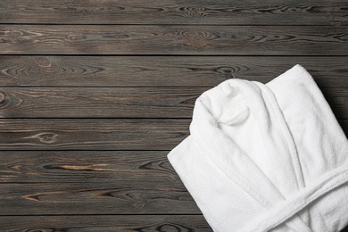 Photo of Clean folded bathrobe on wooden background, top view. Space for text