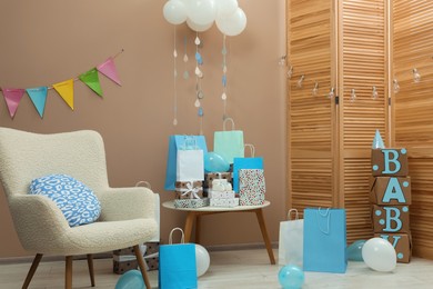 Photo of Baby shower party. Festive decor, gift boxes and bags in stylish room