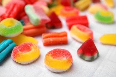 Photo of Many tasty colorful jelly candies on white tiled table, closeup