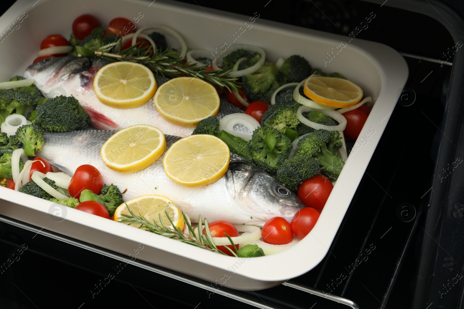 Photo of Raw fish with vegetables and lemon in baking dish into oven