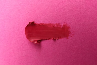 Photo of Smear of beautiful lipstick on pink background, top view