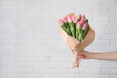 Photo of Girl holding bouquet of beautiful spring tulips near brick wall, closeup with space for text. International Women's Day