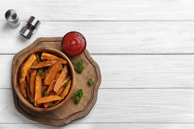 Photo of Bowl with tasty sweet potato fries on wooden background, top view. Space for text