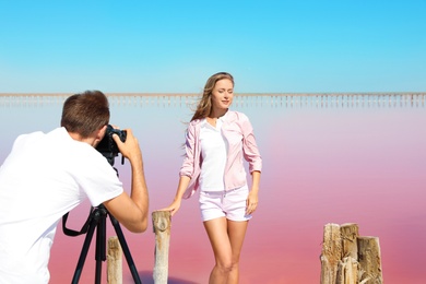 Professional photographer taking photo of woman near pink lake on sunny day