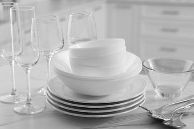 Photo of Different clean dishware, cutlery and glasses on white marble table in kitchen, closeup